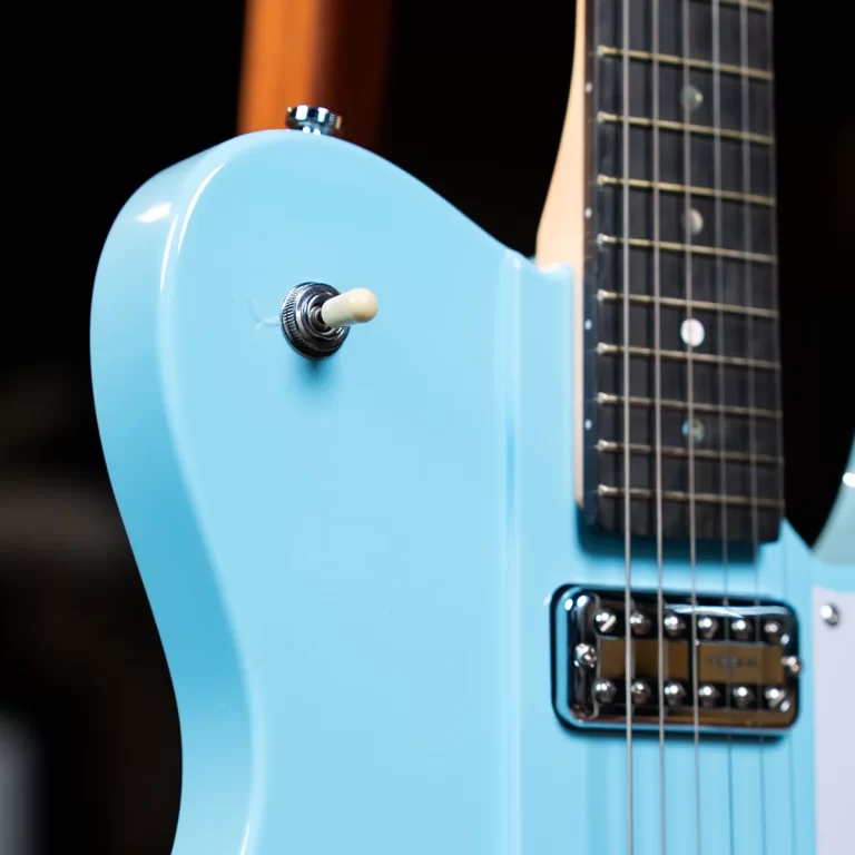 Close-up of a light blue electric guitar body with a white control knob and chrome pickup. ขายราคาพิเศษ