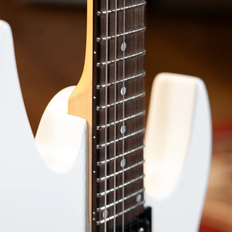 Close-up of a white electric guitar neck, showing the dark fretboard, metal frets, and strings. ขายราคาพิเศษ