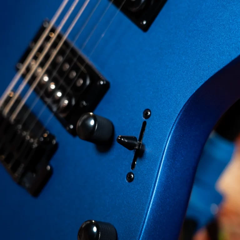 Close-up of a blue electric guitar showing knobs, pickup, and a switch on the body ขายราคาพิเศษ