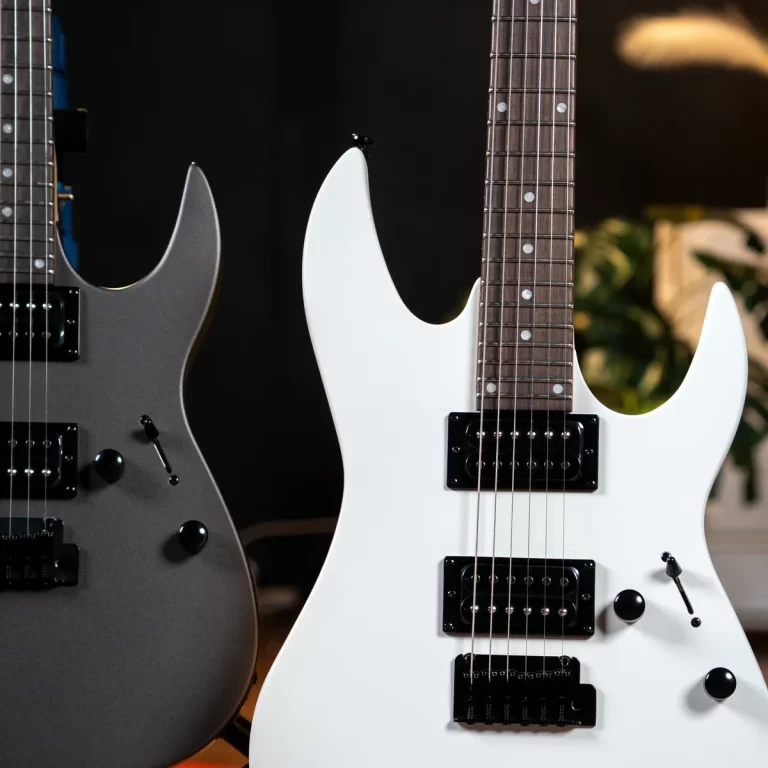 Two electric guitars standing side by side: a white guitar with dual humbucker pickups next to a gray guitar with a darker finish. ขายราคาพิเศษ