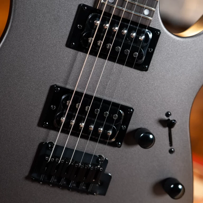 Close-up of a metallic gray electric guitar with two humbucker pickups, strings, and control knobs ขายราคาพิเศษ