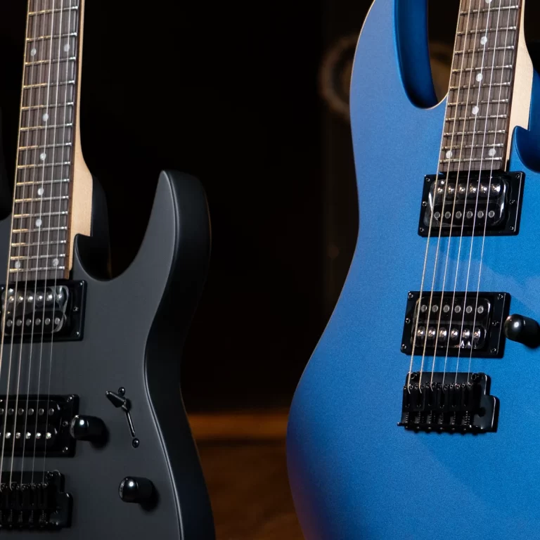 Two electric guitars in close-up: a matte gray guitar on the left and a metallic blue guitar on the right, showing pickups and strings. ขายราคาพิเศษ