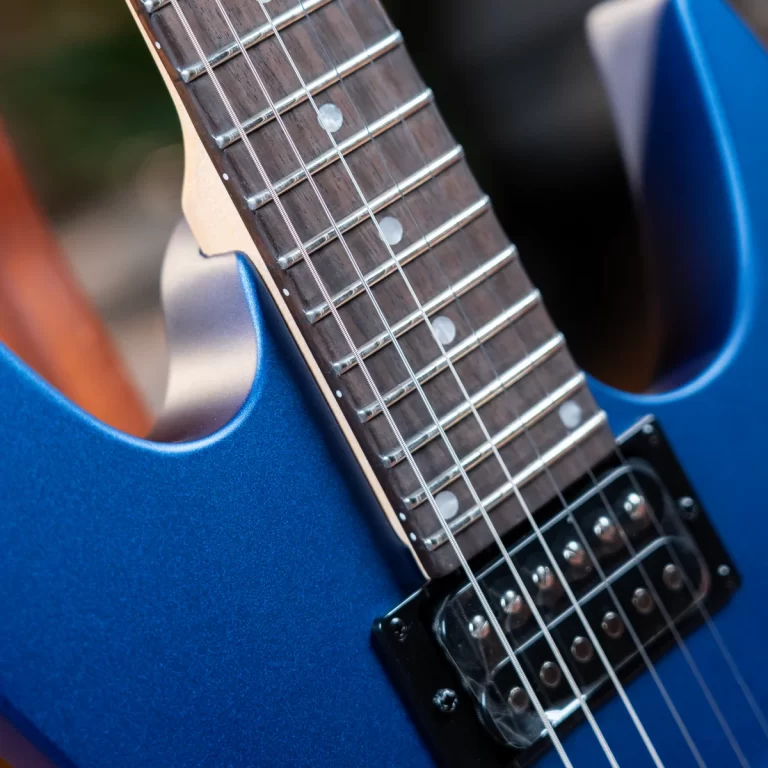 Close-up of a blue electric guitar neck with frets, strings, and fret markers seen at an angle ขายราคาพิเศษ