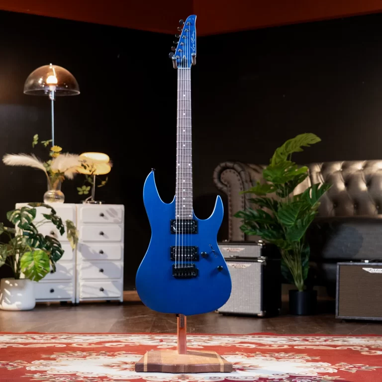 Blue electric guitar on a stand in a cozy studio living room with amplifiers and plants in the background. ขายราคาพิเศษ