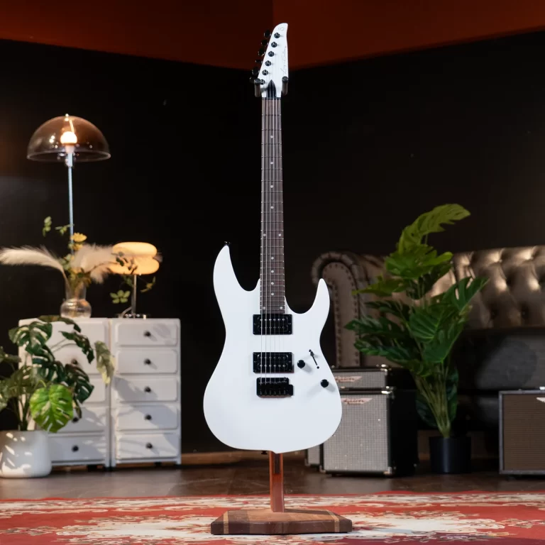 White electric guitar on a stand in a cozy studio with plants and furniture in the background ขายราคาพิเศษ