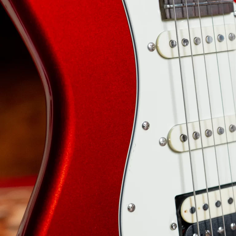 Close-up of a red electric guitar body with a white pickguard, pickups, and strings. ขายราคาพิเศษ