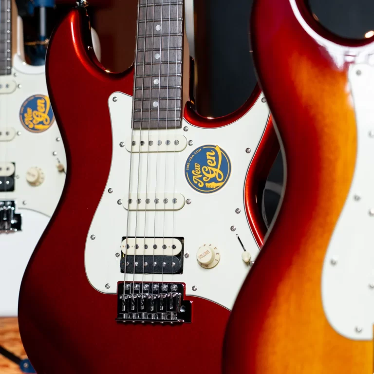 Close-up of a red electric guitar with white pickguard and a New Gen sticker, surrounded by other guitars in a shop display. ขายราคาพิเศษ