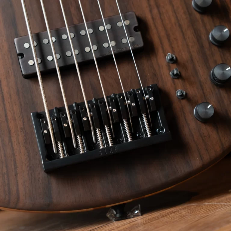 Close-up of an electric guitar bridge and six strings on a dark wood body, with control knobs visible to the right of the image. ขายราคาพิเศษ