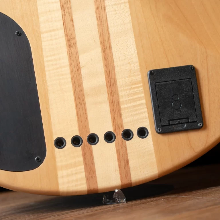 Back of a natural wood electric guitar showing six string ferrule holes and a black rectangular control/battery cover ขายราคาพิเศษ