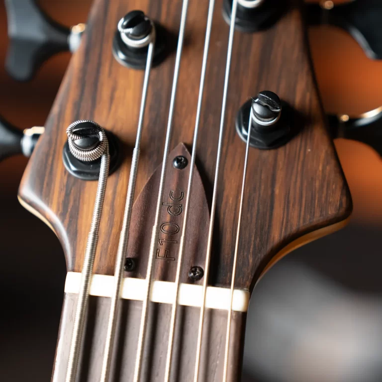 Close-up of a guitar headstock with six strings and tuning pegs on a dark wood finish. ขายราคาพิเศษ