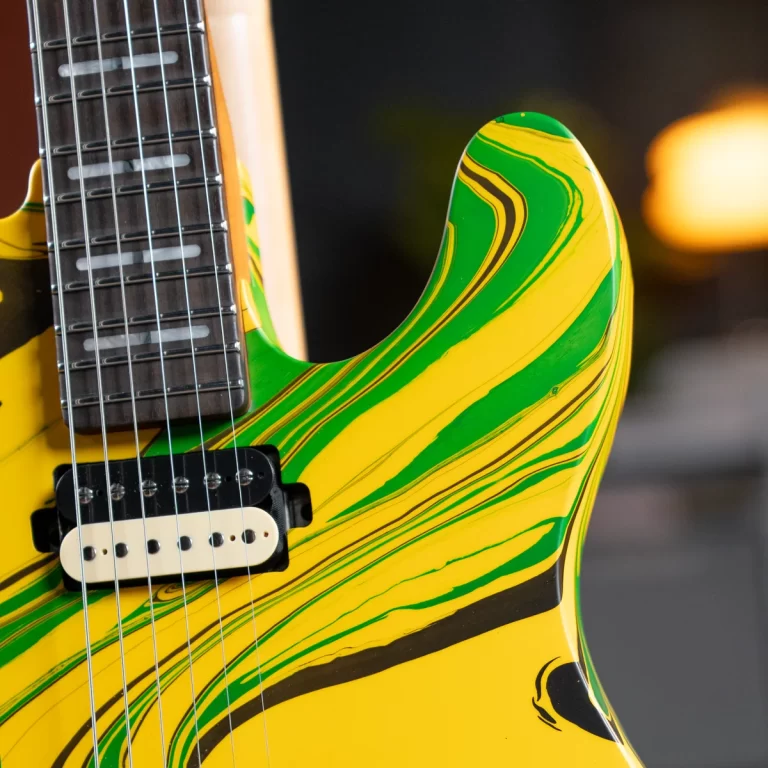 Close-up of a yellow-green swirled electric guitar body with a white single-coil pickup and dark fretboard edge visible to the left. ขายราคาพิเศษ