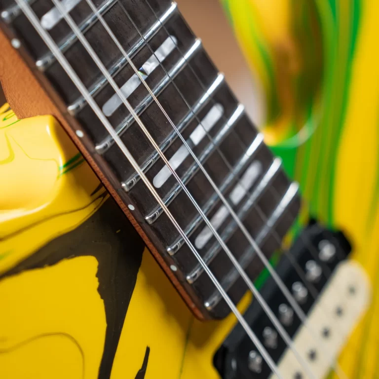 Close-up of a yellow electric guitar neck with frets and strings ขายราคาพิเศษ