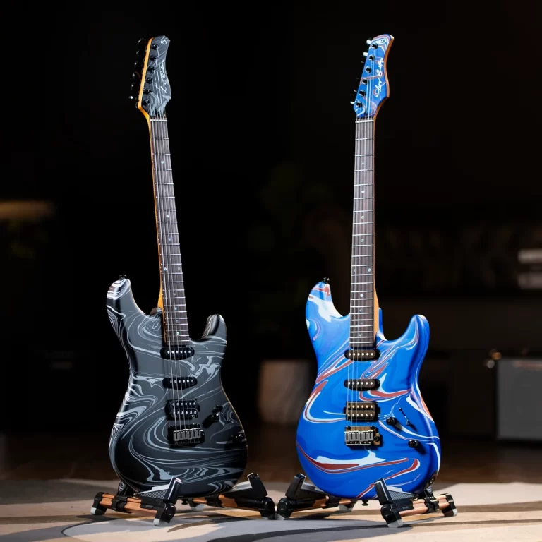 Two electric guitars with marbled bodies on stands in a dark studio, one gray-black swirled and the other blue with red and white swirls. ขายราคาพิเศษ