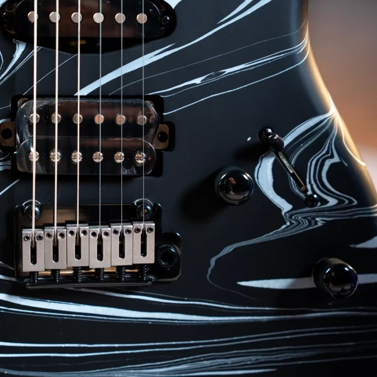 Close-up of a black electric guitar with white marbled stripes, showing the pickups, strings, and bridge detail. ขายราคาพิเศษ