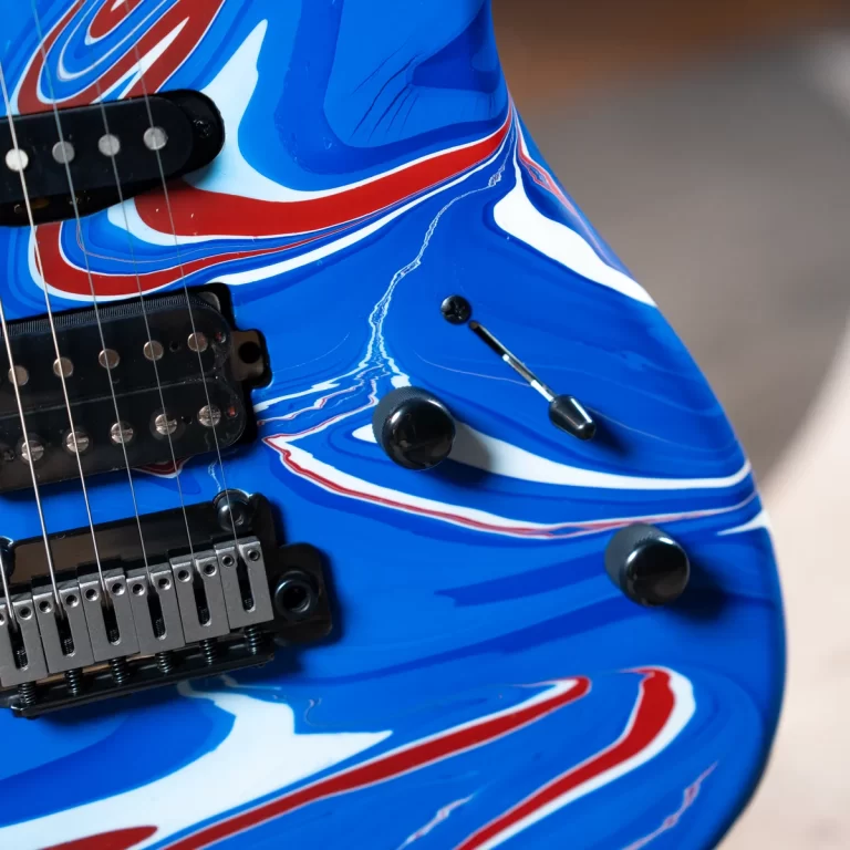 Blue electric guitar body with red and white swirl finish, showing pickups and control knobs in a close-up. ขายราคาพิเศษ
