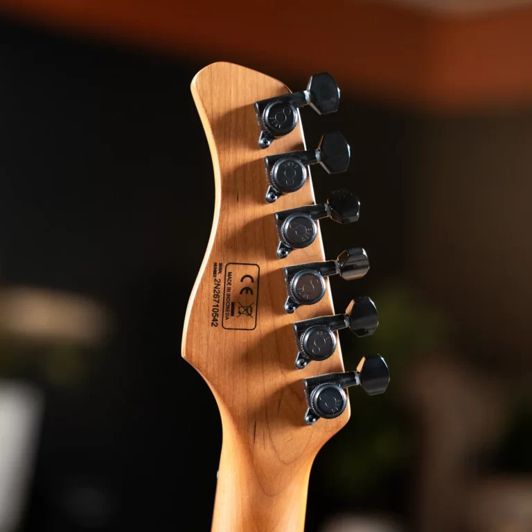 Close-up of a guitar headstock showing six tuning pegs on a wooden neck, with small factory markings visible on the back of the headstock. ขายราคาพิเศษ