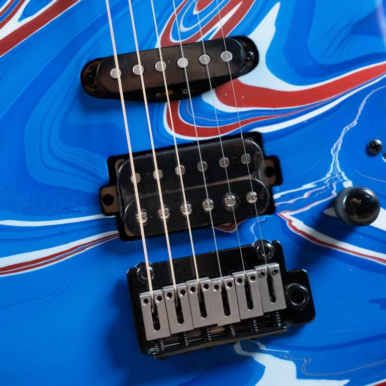 Close-up of a blue marbled electric guitar showing pickups and a chrome bridge with six strings ขายราคาพิเศษ