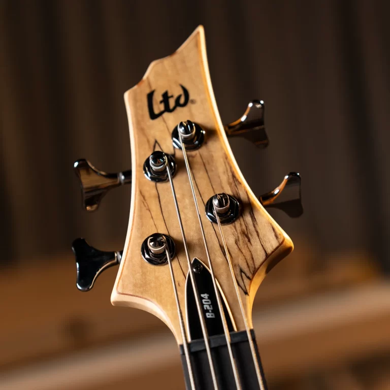 Close-up of a wooden guitar headstock with tuning pegs, four strings, and the 'Ltd' logo visible. ขายราคาพิเศษ