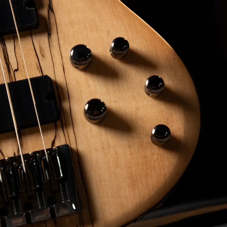 Close-up of a natural-finish guitar body with four chrome control knobs and strings visible along the fret area. ขายราคาพิเศษ