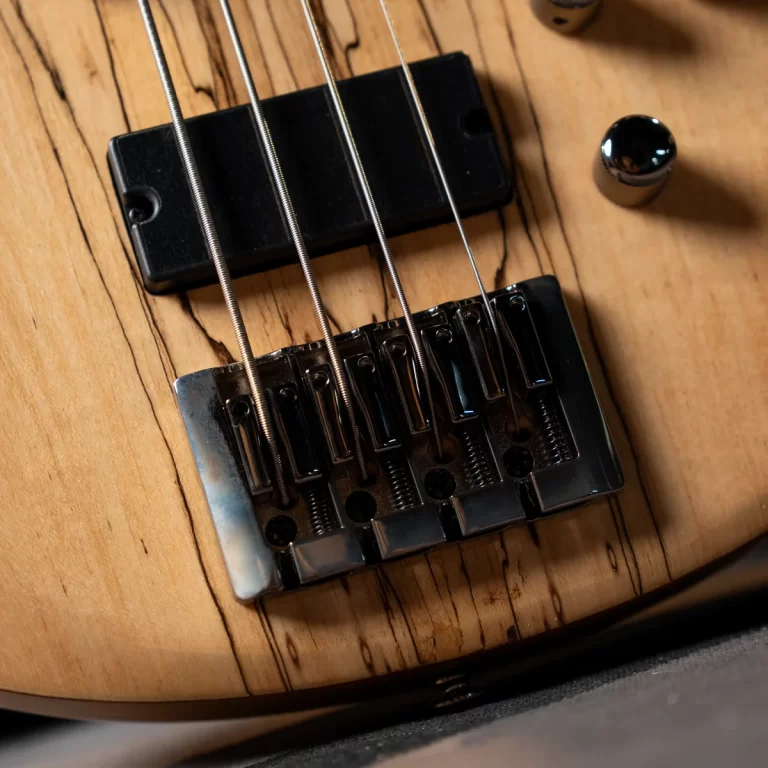 Close-up of an electric guitar bridge with six steel strings over metal saddles on a light wood body. ขายราคาพิเศษ