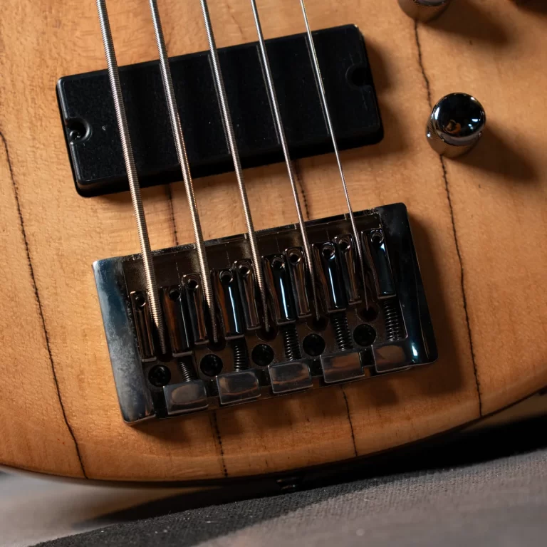 Close-up of an electric guitar bridge with six steel strings over a wooden body. ขายราคาพิเศษ