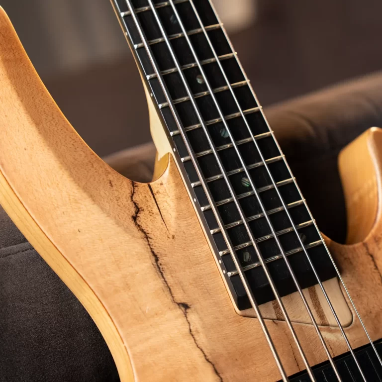 Close-up of a natural wood guitar neck and body with six steel strings and a visible grain crack along the body edge. ขายราคาพิเศษ