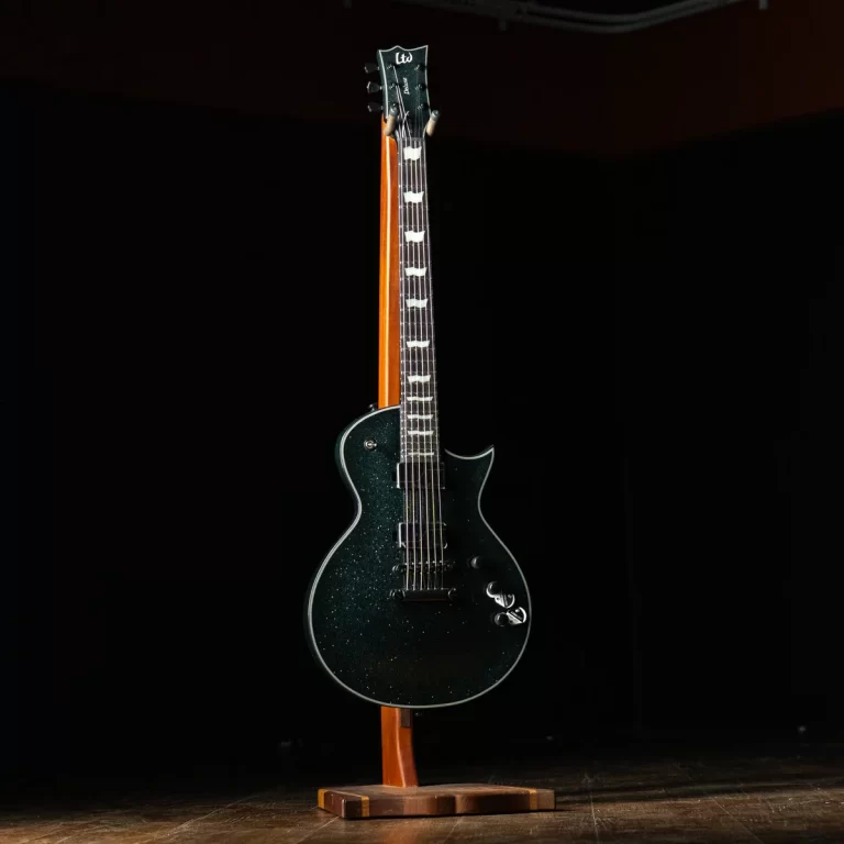 Electric guitar with a dark, sparkling finish on a wooden stand, illuminated on a dark stage. ขายราคาพิเศษ