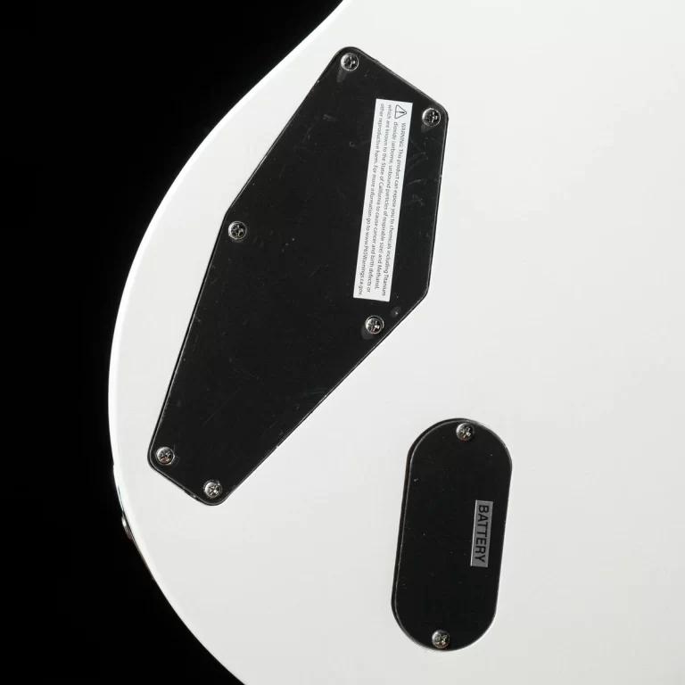 Close-up of a white electric guitar body showing black back plates and a battery compartment labeled BATTERY. ขายราคาพิเศษ