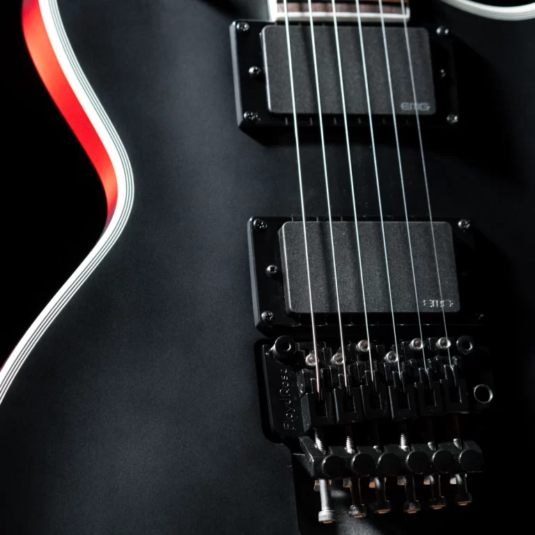 Close-up of a black electric guitar body showing strings, pickups, and a tremolo bridge with white edge binding nearby. ขายราคาพิเศษ