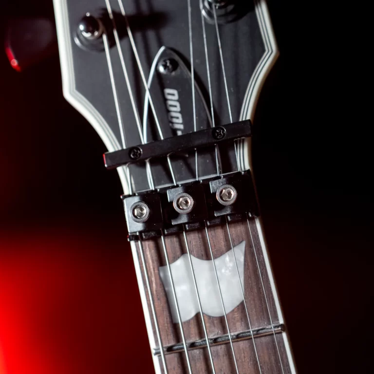 Close-up of a black guitar headstock with six strings and a white pick-shaped fretboard inlay near the nut. ขายราคาพิเศษ