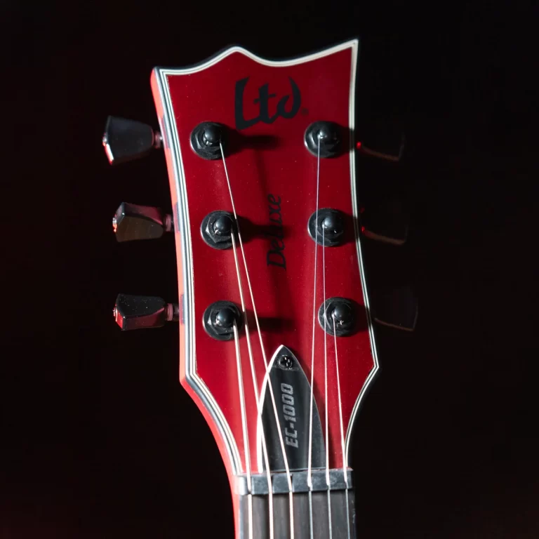 Close-up of a red guitar headstock with six black tuners and strings, showing the LTD logo and 'Deluxe' engraving. ขายราคาพิเศษ