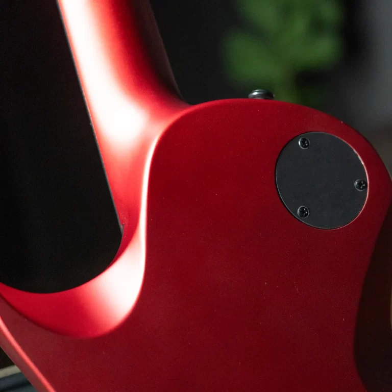 Close-up of a red electric guitar body showing a black circular back plate with screws ขายราคาพิเศษ