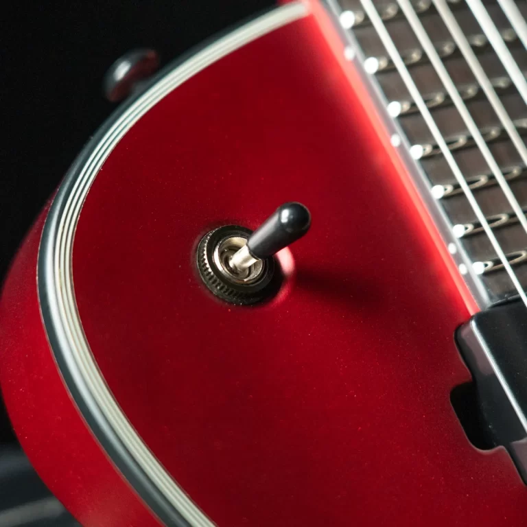 Close-up of a glossy red guitar body with a black toggle switch near the edge. ขายราคาพิเศษ