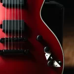 Close-up of a red electric guitar body with strings, two black knobs, a white push/pull switch, and white edge binding along the side. ขายราคาพิเศษ