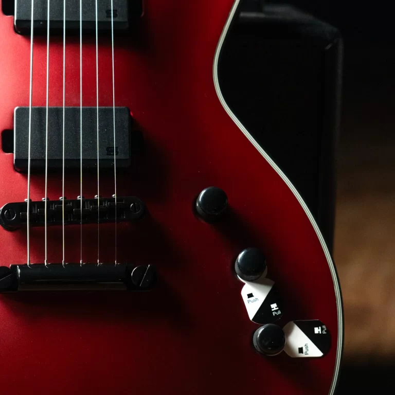 Close-up of a red electric guitar body with strings, two black knobs, a white push/pull switch, and white edge binding along the side. ขายราคาพิเศษ