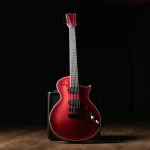 Red electric guitar with a double-cutaway body resting on a small black amplifier in a dim studio. ลดราคาพิเศษ