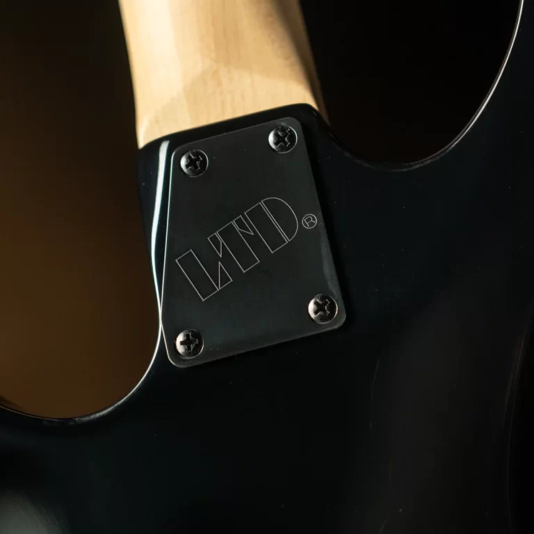 Close-up of a black electric guitar back showing the neck plate with four screws and a subtle engraved logo ขายราคาพิเศษ