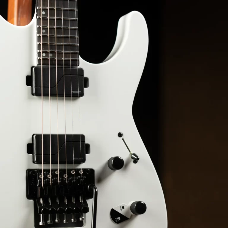 Close-up of a white electric guitar showing pickups, strings, and a black tremolo bridge against a dark background. ขายราคาพิเศษ
