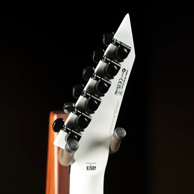 Close-up of a white guitar headstock with black tuning pegs against a dark background. ขายราคาพิเศษ