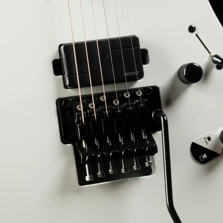 Close-up of a white electric guitar bridge with a locking tremolo system and six strings intact on a white body surface. ขายราคาพิเศษ