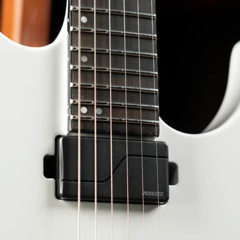 Close-up of a white electric guitar neck with dark fretboard, six strings and a Fishman pickup visible beneath the strings ขายราคาพิเศษ