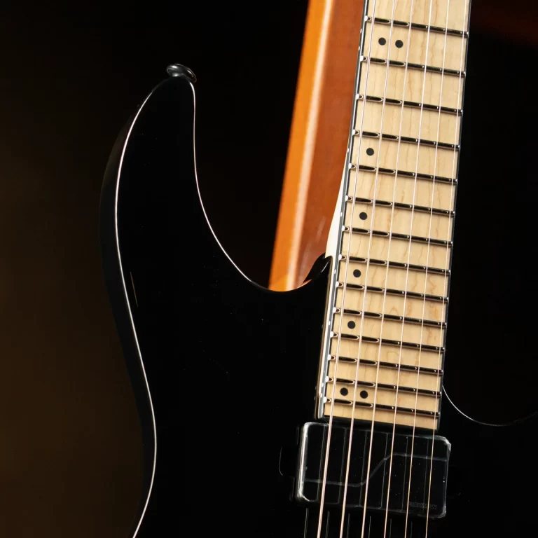 Close-up of a black electric guitar body and maple fretboard with strings against a dark background. ขายราคาพิเศษ