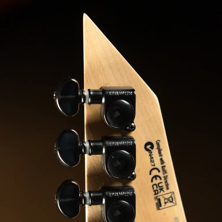 Close-up of a light wood guitar headstock with four black Grover tuning pegs against a dark background, showing detail of the hardware. ขายราคาพิเศษ