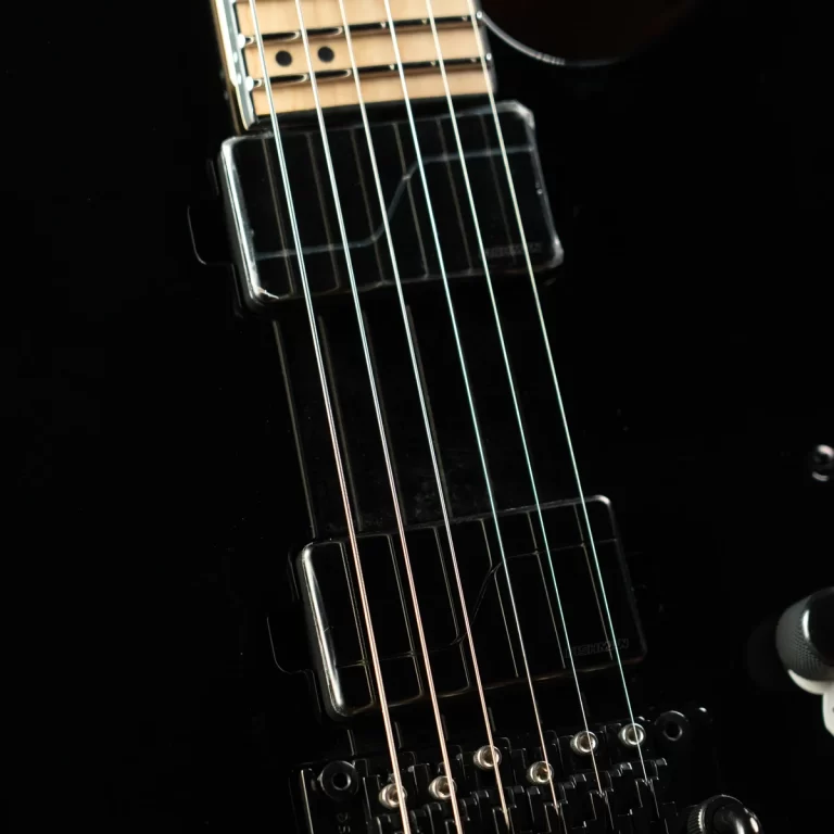Close-up of a black electric guitar neck showing six strings over pickups and a dark body background, focusing on strings and pickups sequence. ขายราคาพิเศษ