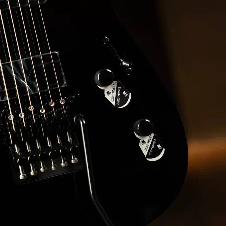 Close-up of a black electric guitar showing strings, bridge saddles, and two chrome control knobs on a glossy body. ขายราคาพิเศษ