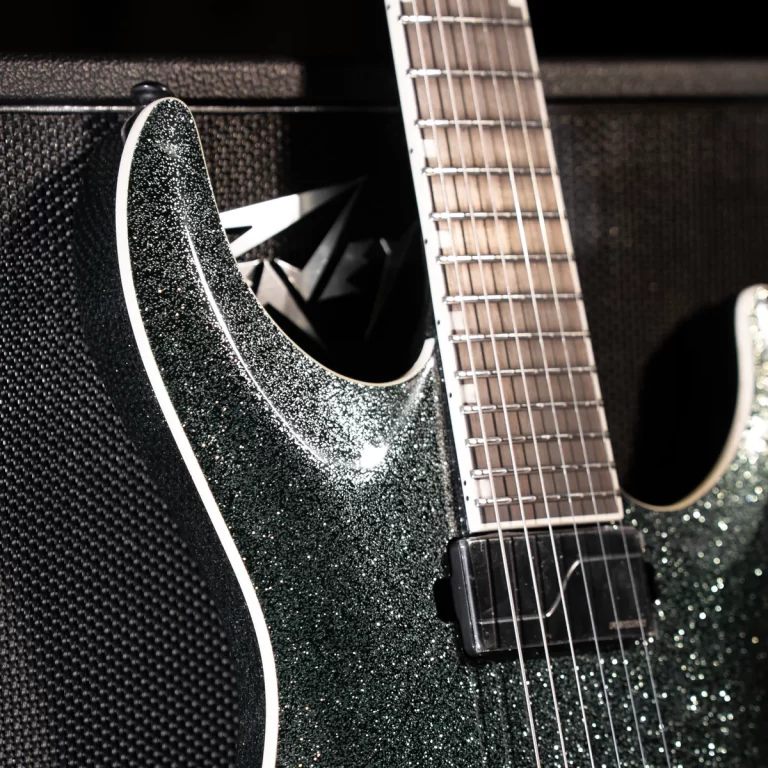 Close-up of a glittery dark-green electric guitar body with neck and pickup visible against a textured black background. ขายราคาพิเศษ
