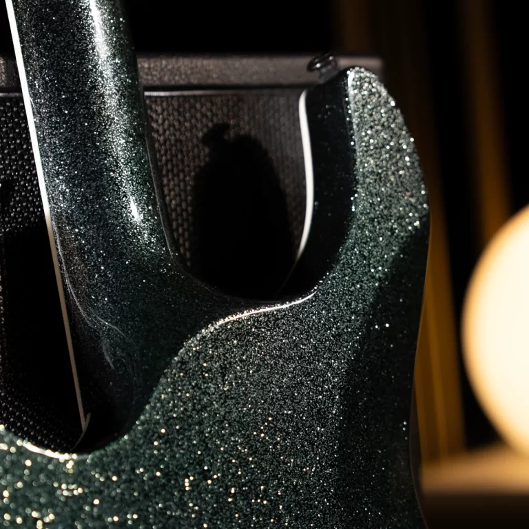 Close-up of a sparkling dark green electric guitar body with a curved cutout and white binding. ขายราคาพิเศษ