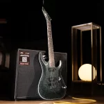 Sparkly dark green electric guitar resting on a black amplifier with a yellow instrument cable, set on a dark stage. ลดราคาพิเศษ