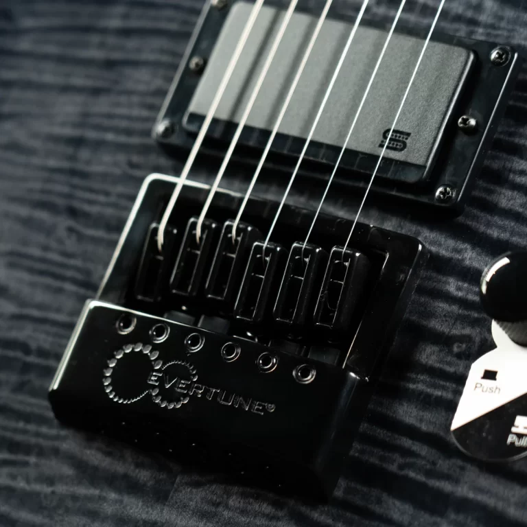 Close-up of a black electric guitar bridge with six saddles and curved tremolo plate, strings spanning over pickups; EverTune logo visible on the bridge plate. ขายราคาพิเศษ