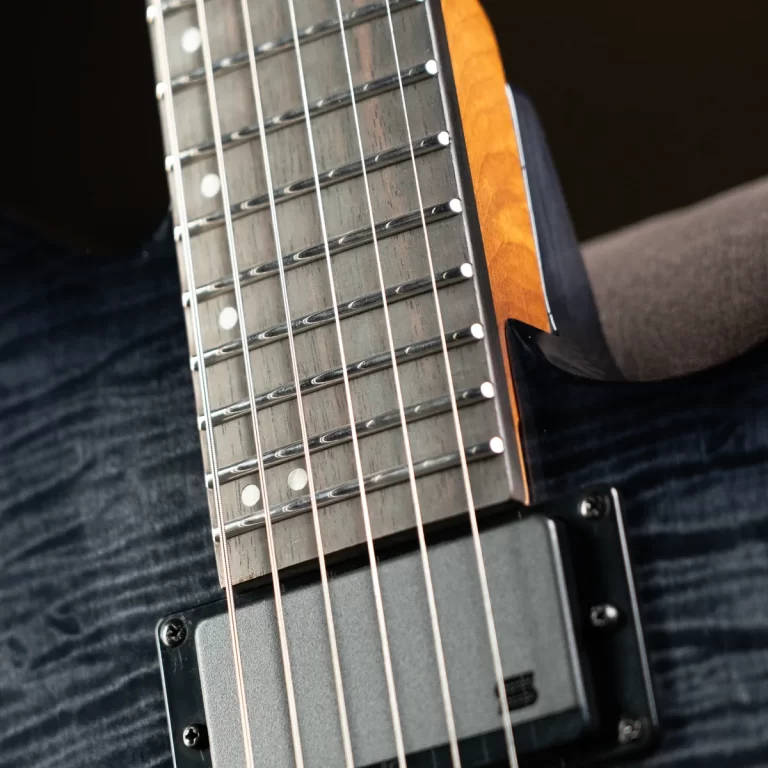 Close-up of an electric guitar neck with metal frets, strings, and dot inlays, angled over a dark body with a pickup below. ขายราคาพิเศษ